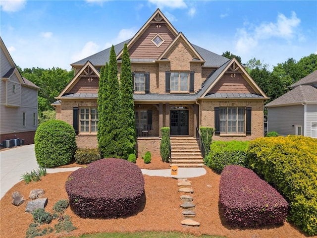 craftsman-style home featuring brick siding, central AC unit, and a standing seam roof