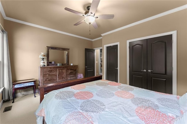 carpeted bedroom featuring ornamental molding, a ceiling fan, two closets, and visible vents