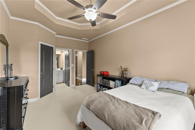 bedroom with crown molding, baseboards, ensuite bathroom, light colored carpet, and a tray ceiling