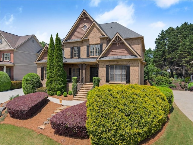 craftsman-style house featuring brick siding, a porch, stairway, a standing seam roof, and metal roof