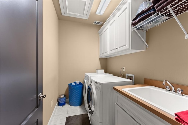 laundry area featuring washing machine and clothes dryer, light tile patterned flooring, cabinet space, a sink, and visible vents