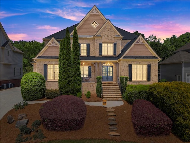view of front of house featuring brick siding, a standing seam roof, and french doors