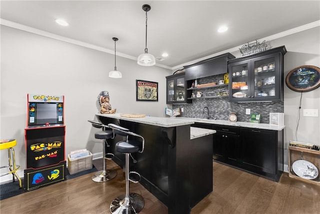 bar with backsplash, wet bar, pendant lighting, ornamental molding, and dark wood-type flooring