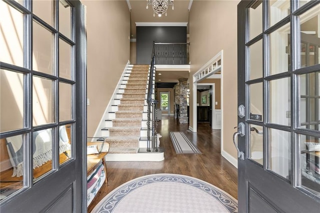 foyer featuring ornamental molding, stairs, a towering ceiling, decorative columns, and dark wood finished floors