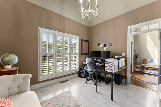 home office with a chandelier, baseboards, wood finished floors, a towering ceiling, and visible vents
