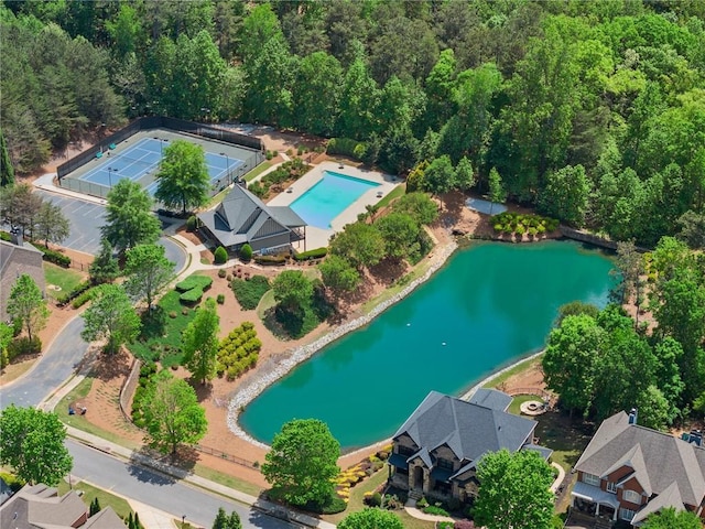 birds eye view of property featuring a water view and a wooded view