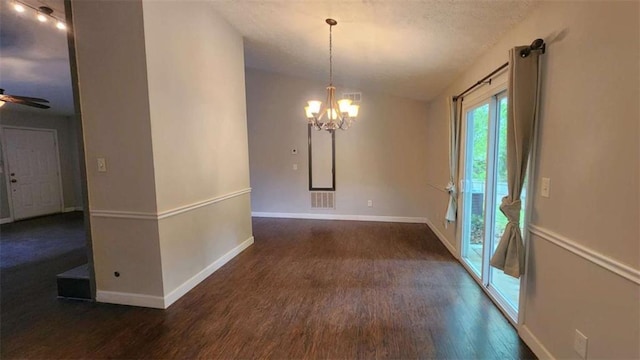 unfurnished dining area featuring visible vents, baseboards, a textured ceiling, wood finished floors, and ceiling fan with notable chandelier