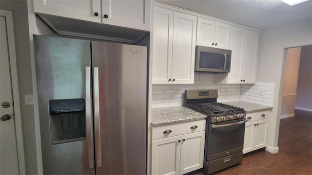 kitchen featuring baseboards, tasteful backsplash, stainless steel appliances, and white cabinets