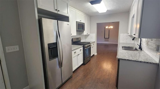 kitchen with a sink, dark wood-type flooring, backsplash, a textured ceiling, and appliances with stainless steel finishes