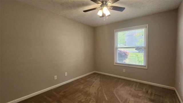 empty room with baseboards, dark carpet, ceiling fan, and a textured ceiling