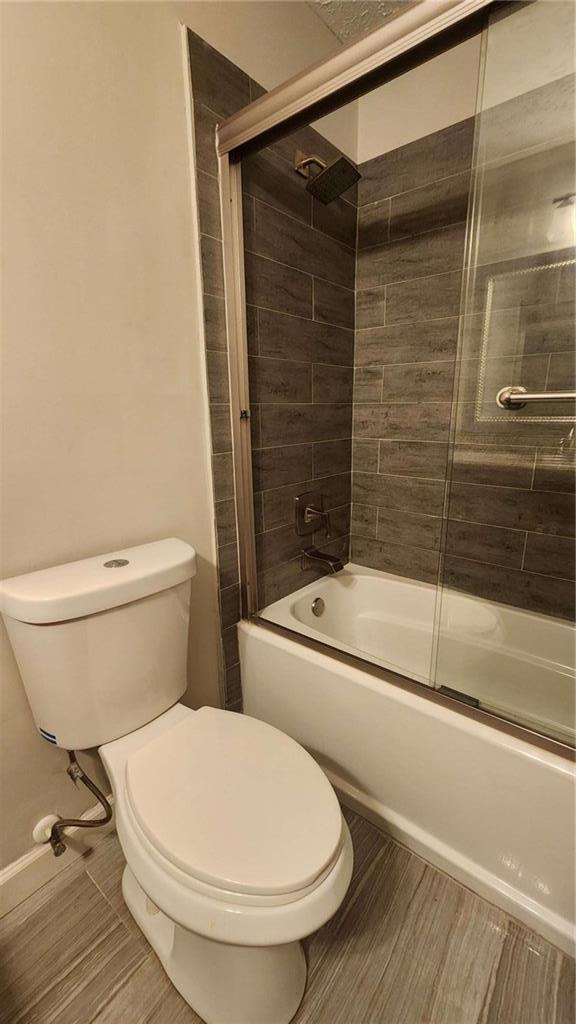 bathroom featuring enclosed tub / shower combo and toilet