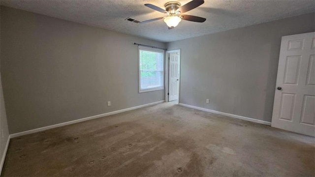 carpeted spare room featuring baseboards, visible vents, a ceiling fan, and a textured ceiling