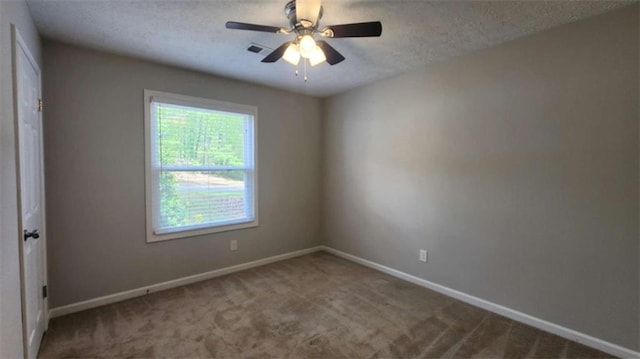 spare room featuring a textured ceiling, carpet flooring, visible vents, baseboards, and a ceiling fan
