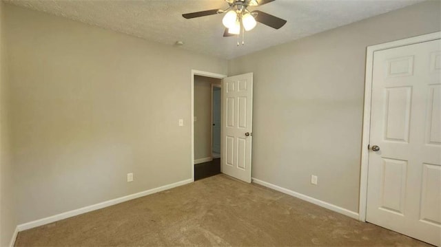 unfurnished bedroom with baseboards, a ceiling fan, a textured ceiling, and carpet