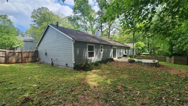 view of home's exterior featuring a chimney, a fenced backyard, a yard, and a patio area