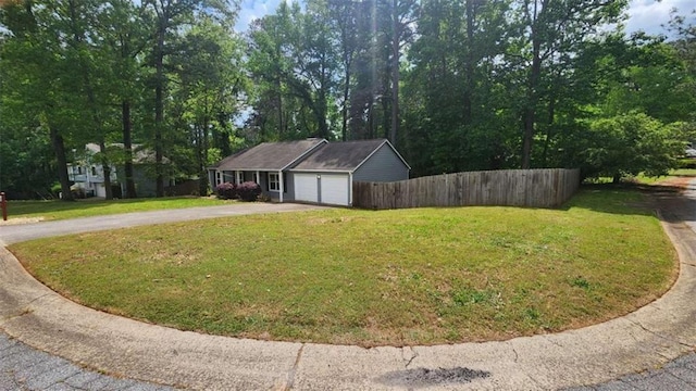 exterior space featuring driveway, fence, a front lawn, and a garage