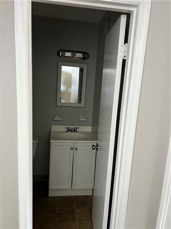 bathroom with toilet, vanity, and tile patterned floors