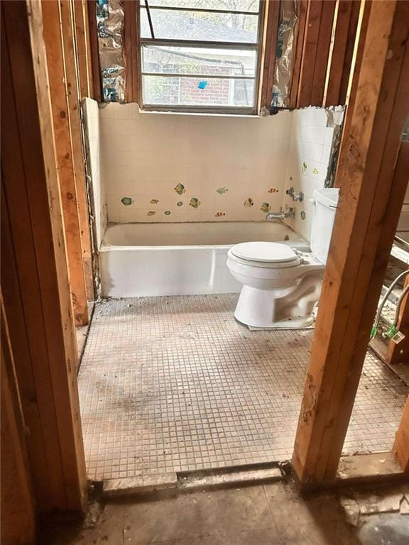 bathroom with a tub to relax in and toilet