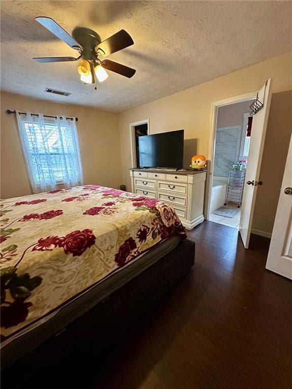 bedroom with ensuite bathroom, dark hardwood / wood-style flooring, a textured ceiling, and ceiling fan