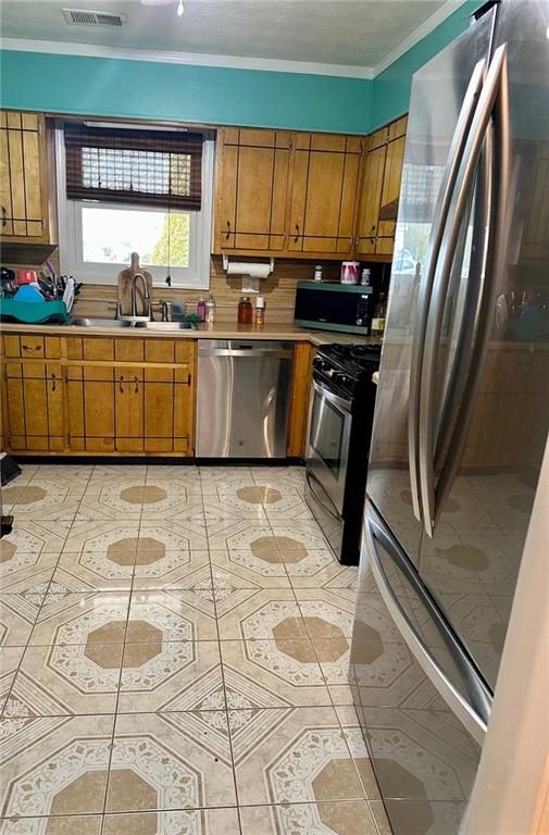 kitchen featuring crown molding, stainless steel appliances, sink, and decorative backsplash