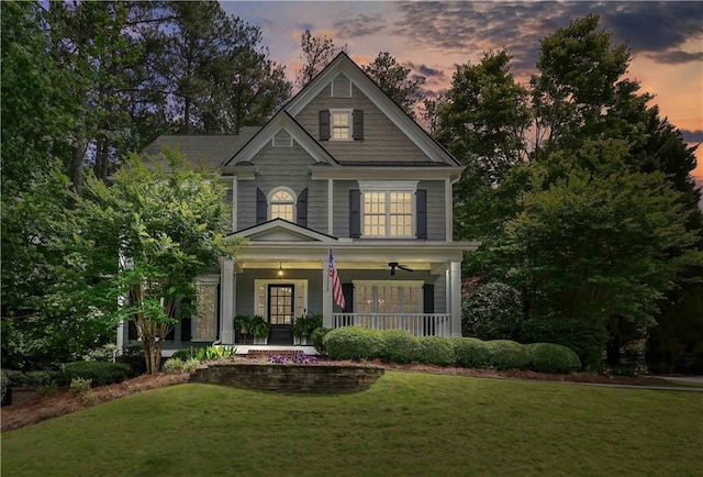 view of front facade with ceiling fan, a porch, and a front yard