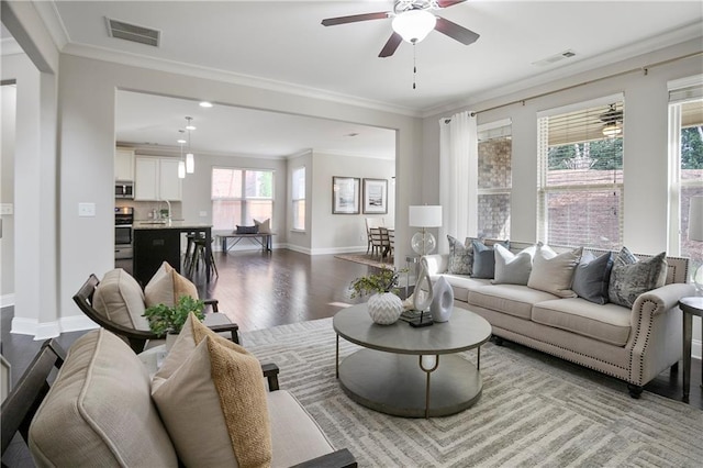 living area with visible vents, crown molding, a ceiling fan, and wood finished floors