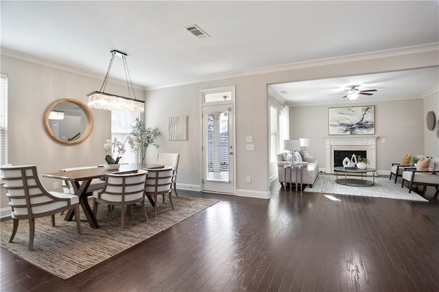 dining area with visible vents, baseboards, ornamental molding, a fireplace, and hardwood / wood-style flooring