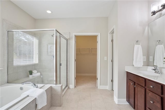 bathroom featuring a spacious closet, a shower stall, a garden tub, tile patterned floors, and vanity