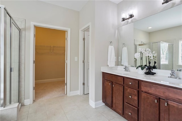 bathroom with a sink, a stall shower, a spacious closet, and tile patterned floors