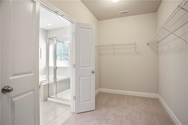 walk in closet featuring light tile patterned floors, light colored carpet, and visible vents