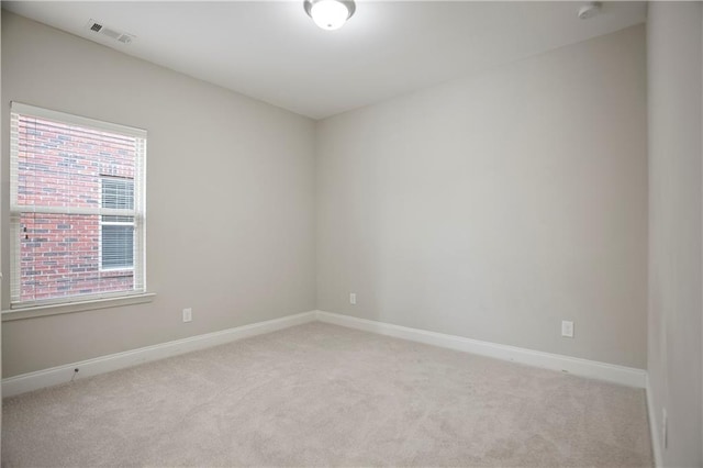 unfurnished room with visible vents, light colored carpet, and baseboards