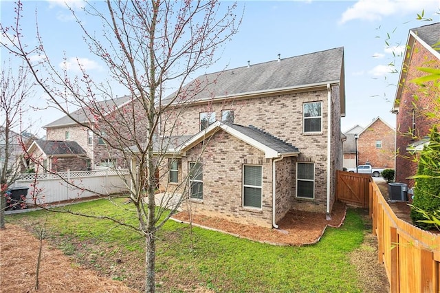 back of property featuring cooling unit, roof with shingles, a fenced backyard, a lawn, and brick siding