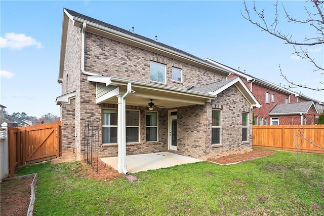 back of property with a fenced backyard, ceiling fan, a lawn, a patio area, and brick siding