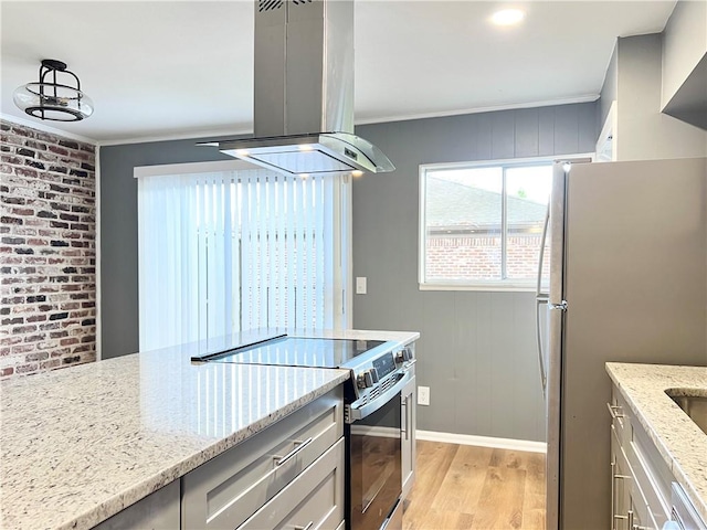 kitchen with ornamental molding, island exhaust hood, stainless steel appliances, light wood-style floors, and light stone countertops