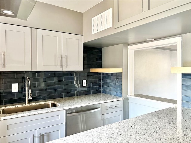 kitchen featuring visible vents, backsplash, dishwasher, light stone counters, and a sink