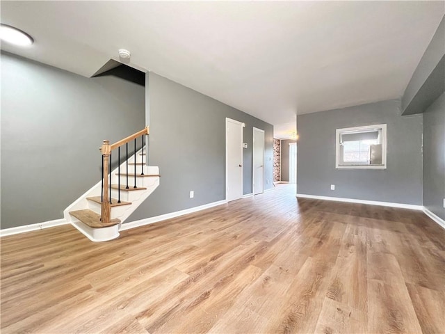 unfurnished living room with stairway, wood finished floors, and baseboards