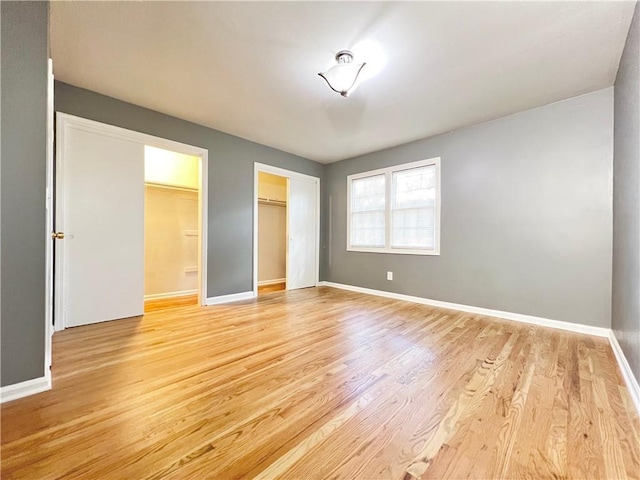 unfurnished bedroom featuring light wood-style floors, baseboards, and a closet