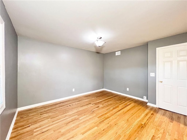 empty room featuring visible vents, baseboards, and light wood finished floors