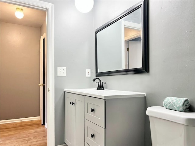 bathroom featuring vanity, toilet, wood finished floors, and baseboards