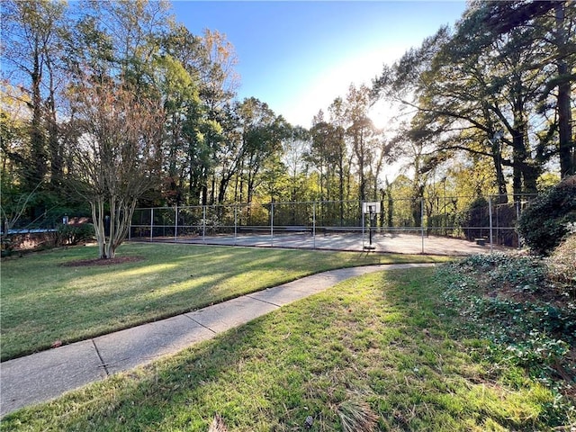 view of community featuring a tennis court, a lawn, and fence