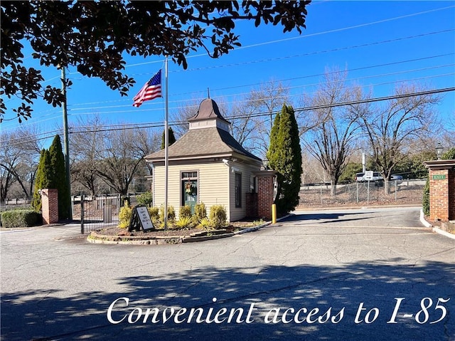 exterior space featuring a gate, a shingled roof, and fence