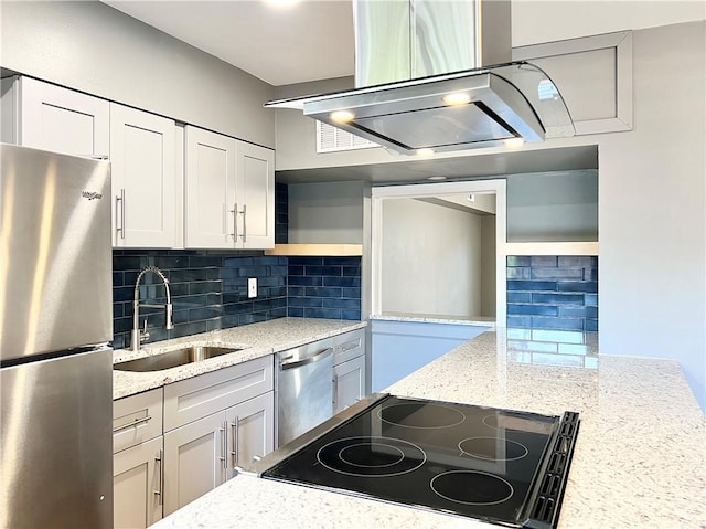 kitchen featuring light stone countertops, a sink, stainless steel appliances, white cabinetry, and backsplash