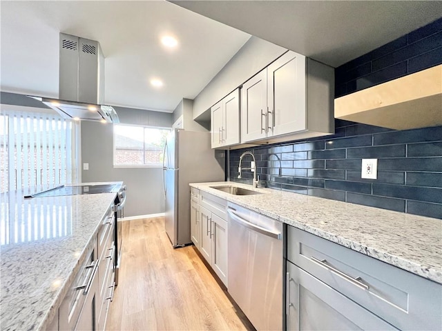 kitchen with light wood finished floors, a sink, decorative backsplash, stainless steel appliances, and island range hood