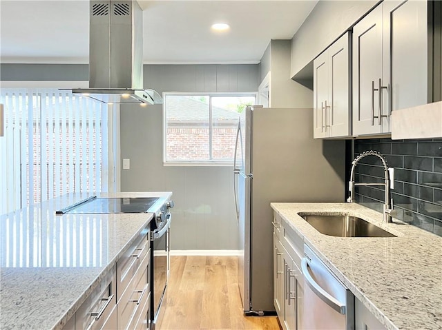 kitchen featuring light wood-type flooring, a sink, tasteful backsplash, stainless steel appliances, and island range hood