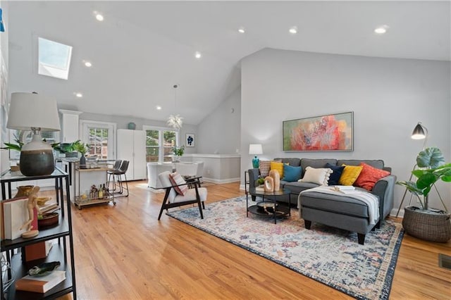 living area featuring light wood-style floors, a skylight, high vaulted ceiling, and recessed lighting