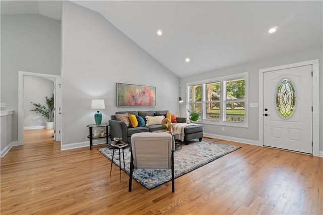 living room featuring high vaulted ceiling, baseboards, and light wood finished floors