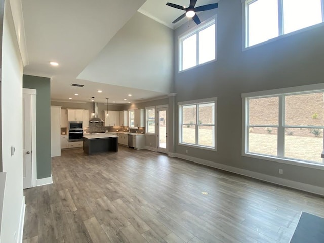 3355 Hillshire Dr, Cumming, GA 30028 - unfurnished living room featuring ceiling fan, crown molding, baseboards, a towering ceiling, and wood finished floors