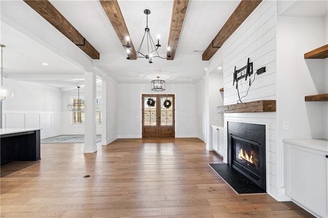 foyer entrance with a fireplace with flush hearth, beamed ceiling, light wood-style flooring, and an inviting chandelier