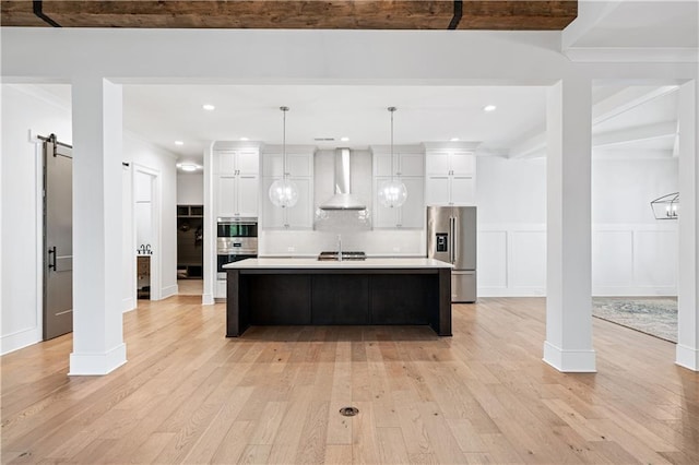 39 Telfair Ct, Acworth, GA 30101 - kitchen with stainless steel appliances, wall chimney exhaust hood, a barn door, light wood-style floors, and light countertops