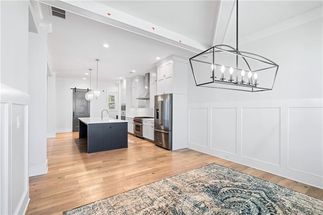 kitchen featuring a decorative wall, a barn door, a sink, wall chimney range hood, and high quality appliances